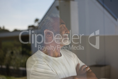 Senior man standing with arms crossed at home