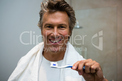 Man holding toothbrush with toothpaste in bathroom