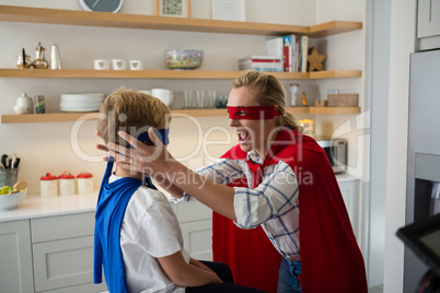 Mother and son pretending to be superhero in the kitchen