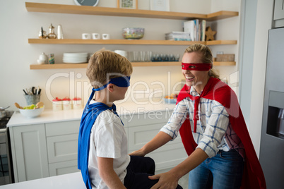 Mother and son pretending to be superhero in the kitchen