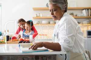 Senior woman looking at recipe book in kitchen