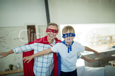 Mother and son pretending to be superhero in living room