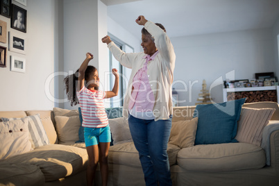 Grandmother and granddaughter dancing in living room