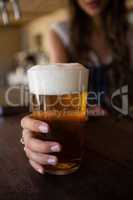 Close-up of barmaid holding beer glass