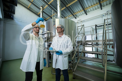 Scientists examining beer in beaker