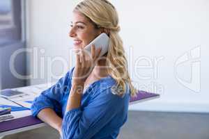 Female architect talking on mobile phone in office