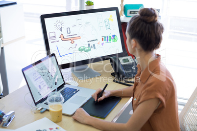 Female executive working over graphic tablet at her desk