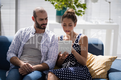 Male and female executives using digital tablet on a sofa