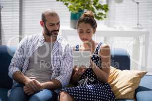Male and female executives using digital tablet on a sofa
