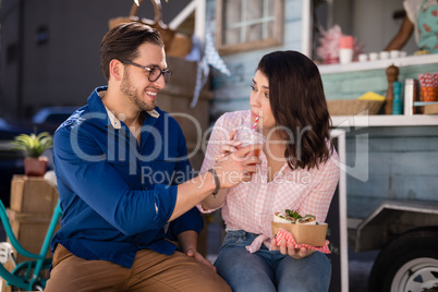 Man feeding juice to woman