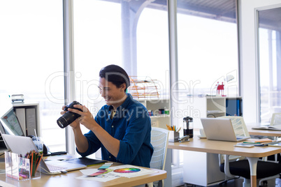 Male executive reviewing captured photograph at his desk
