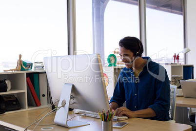 Male executive in headset working over computer at his desk