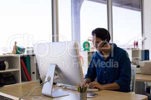 Male executive in headset working over computer at his desk