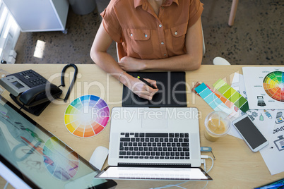 Female executive working over graphic tablet at her desk