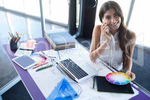 Female executive talking on mobile phone at her desk