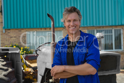 Worker standing with arms crossed near tractor