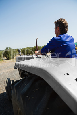 Rear view of worker driving a tractor
