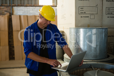 Worker using laptop in olives factory