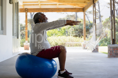 Senior man exercising on exercise ball in the porch