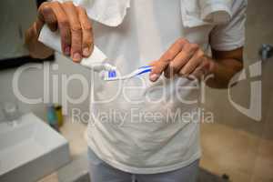 Mid-section of man putting toothpaste on toothbrush