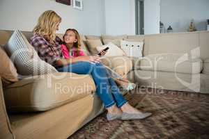 Mother and daughter watching television in the living room