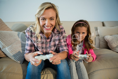 Mother and daughter playing video game in the living room