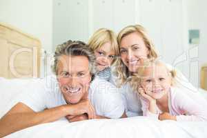 Happy family lying together on bed in bedroom