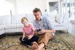 Father and son playing video game in living room