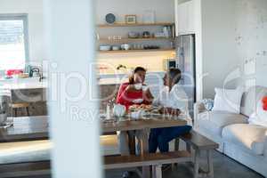 Happy mother and daughter having tea on dining table