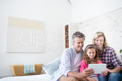 Smiling family using digital tablet together in living room