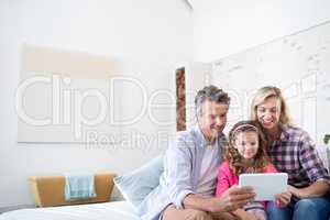 Smiling family using digital tablet together in living room