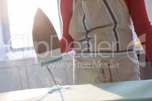 Woman ironing shirt on ironing board in kitchen