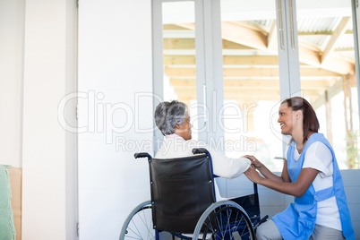 Female doctor interacting with senior woman on wheelchair