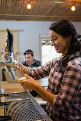 Barmaid pouring beer from tap in glass