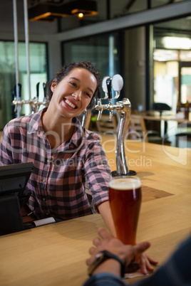 Happy barmaid serving drink to man