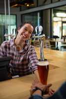 Happy barmaid serving drink to man