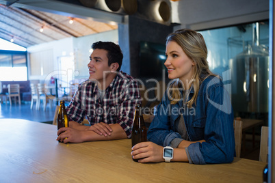 Smiling friends looking away while having beer