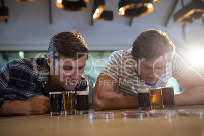 Male friends looking at beer glass at bar counter