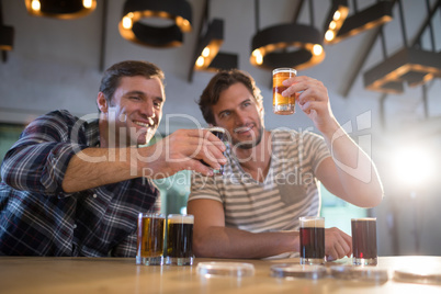 Smiling friends holding beer glass at bar counter