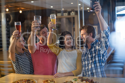 Cheerful friends holding beer glass in bar