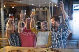 Cheerful friends holding beer glass in bar