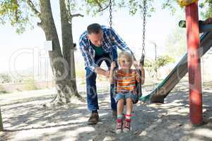 Father pushing son sitting on swing