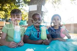 Smiling children with face paint having drinks at park
