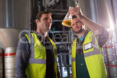 Coworkers examining beer in beaker