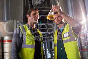 Coworkers examining beer in beaker