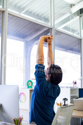 Male executive stretching hands at his desk