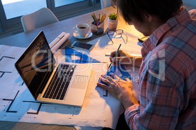 Male architect working on blueprint at his desk