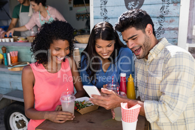 Friends using mobile phone at food truck van