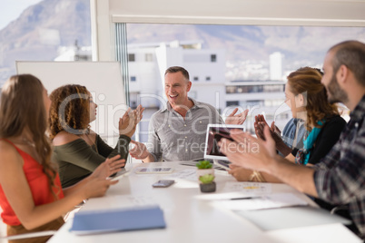 Colleagues applauding man while presentation