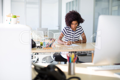 Female executive writing on paper at her desk